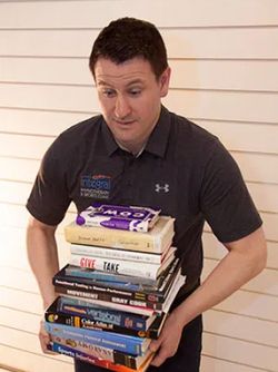Adam Giesbrecht carrying a stack of books.